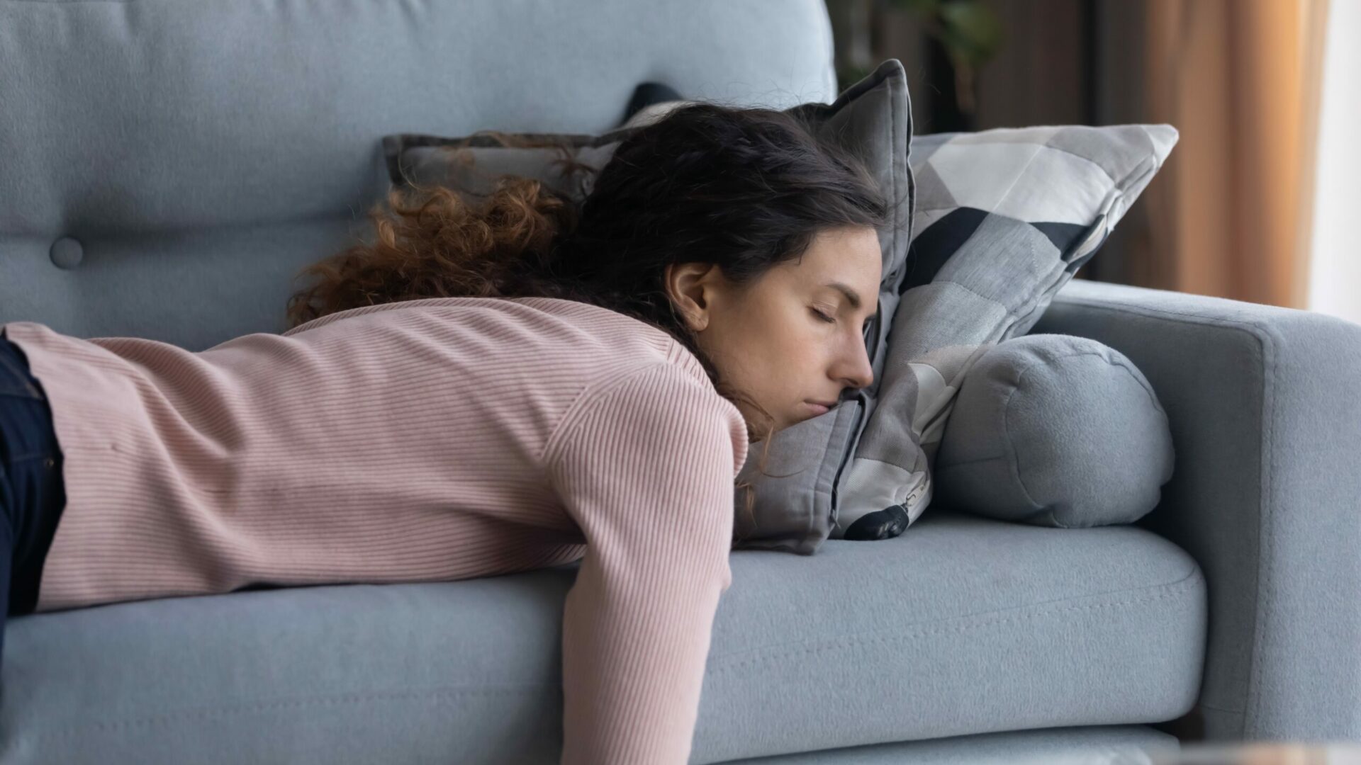 Exhausted,Young,Caucasian,Woman,Lying,On,Comfortable,Sofa,In,Living