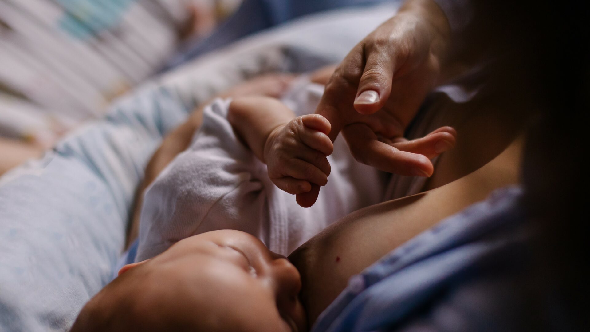 Young,Mother,Breastfeeds,Her,Newborn,At,Home.,Low,Key,Dark